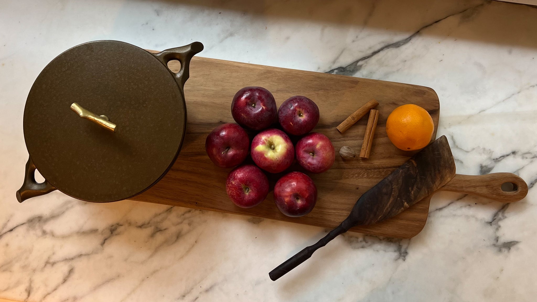 board with apples, dutch oven, and spatula