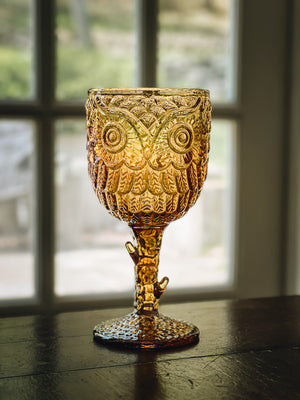 A green glass goblet embossed with an owl face design